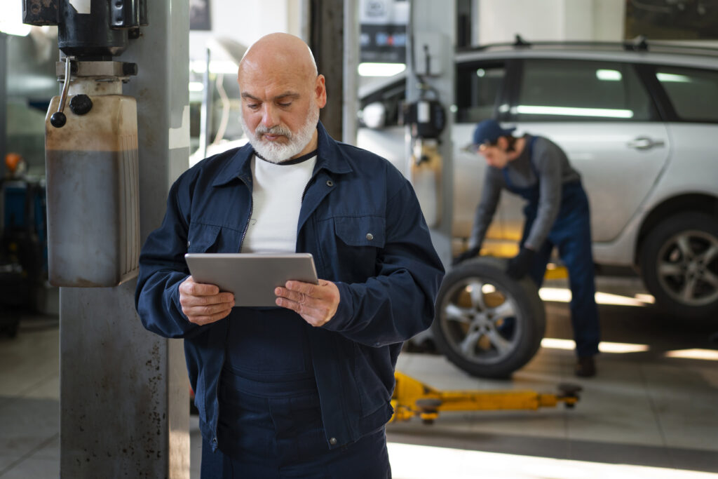 male car mechanic using tablet device car repair shop